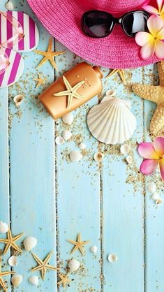 a pink hat, sunglasses and starfish on a blue wooden background with shells and flowers