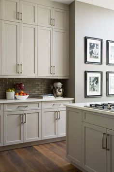 a kitchen with white cabinets and pictures on the wall