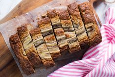 sliced banana bread sitting on top of a cutting board next to a pink and white towel