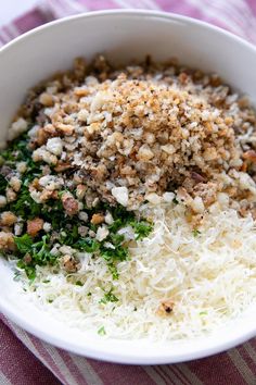 a white bowl filled with food on top of a purple and white striped table cloth