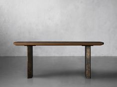 a wooden table sitting on top of a cement floor in front of a white wall