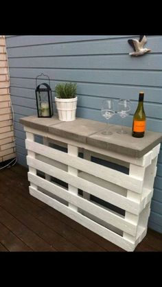 a table made out of pallets with wine glasses on it and a bottle of wine