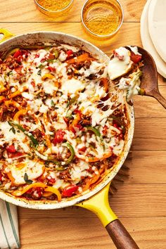 a pizza in a pan on a wooden table next to some glasses and utensils