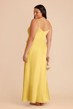 a woman in a yellow dress with her back turned to the camera, looking down