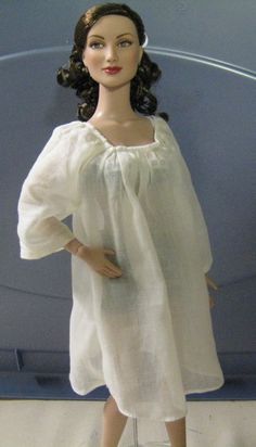 a doll is wearing a white dress and shoes