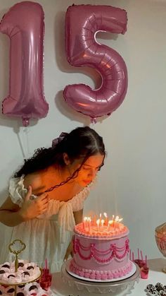 a woman blowing out candles on a pink cake with the number twenty five behind her