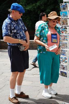 two people standing next to each other in front of a sign with pictures on it