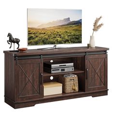 a flat screen tv sitting on top of a wooden entertainment center next to a vase