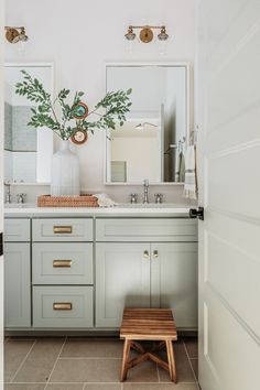 a bathroom with two sinks, mirrors and a stool in front of the sink area