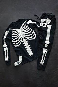 a skeleton sweatshirt and sweatpants on a black surface with silver tape around the bottoms