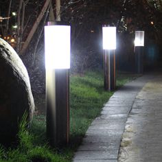 some lights that are on the side of a road in the grass and rocks near by