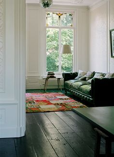 a living room filled with furniture next to a window and a rug on top of a hard wood floor