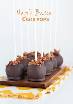 chocolate covered cake pops on a wooden platter with white and orange striped napkins