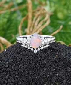 an opal and diamond ring on top of a rock