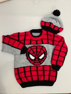 a knitted spiderman sweater and hat on a white surface