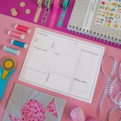 craft supplies laid out on top of a pink table with scissors, tape and paper