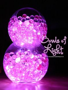 two clear balls with pink lights in them on a purple tablecloth and black background text reads bowle of light