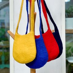 three purses hanging on a wooden stick in front of a white door and window