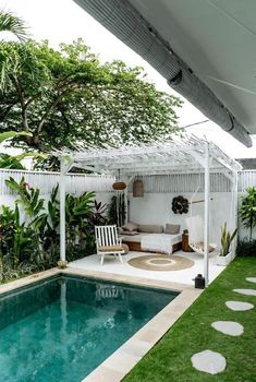 a small pool in the middle of a backyard with a white pergolated roof