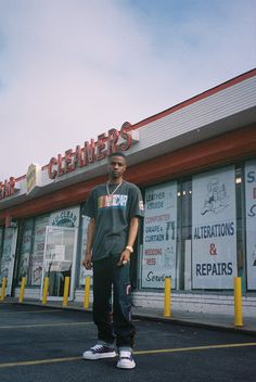 a man standing in front of a cleaner's shop with his foot on the ground