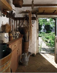 a kitchen with pots, pans and utensils hanging from the ceiling in front of an open door