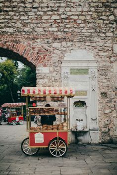 an old fashioned cart selling pastries in front of a brick wall with arches over it