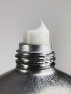 a close up of a silver vase with a white candle in it's center