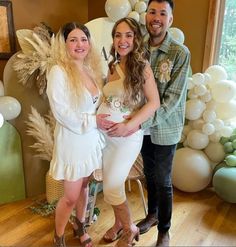 two women and a man standing in front of balloons