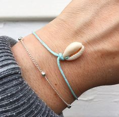 --- S H E L L ~ B R A C E L E T ---  ~ Cowrie Shell on aquamarine soft cord.  ~ Dainty silver plated end beading.  ~ Each bracelet has a self tie closure to fit you perfectly as shown.  ~ Choose your length! Model wears size Small; please see size guide below.  ~ Other colours are available, check out our other listings! Every cowrie shell will vary! ~ G E T ~ T H E ~ S E T ! ~  ~ Like this bracelet set shown in image 1? The silver plated beaded bracelet & cowrie shell bracelet can now be purcha Ocean-inspired Silver Bracelets As Gifts, Adjustable Silver Bracelets With Ocean-inspired Style, Adjustable Silver Bracelet With Ocean-inspired Style, Silver Adjustable Ocean-inspired Bracelets, Adjustable Silver Ocean-inspired Bracelets, Handmade Silver Ocean-inspired Bracelets, Silver Strand Bracelets As Gift, Handmade Sterling Silver Bracelets For Beach, Handmade Sterling Silver Bracelet For Beach