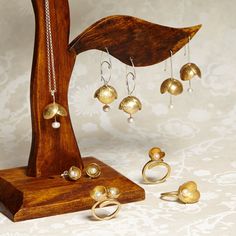 an assortment of jewelry is displayed on a wooden stand and in front of a floral wallpaper