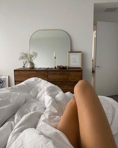 a woman laying on top of a bed covered in white sheets