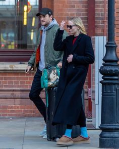 the man and woman are walking down the street together, one is carrying a handbag