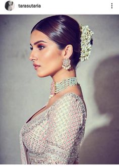 a woman in a silver dress with pearls on her head and jewelry hanging from her neck