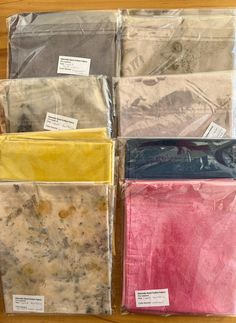 four different colored bags sitting on top of a wooden table covered in plastic wrappers