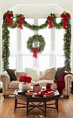 a living room decorated for christmas with wreaths and poinsettis on the windowsill