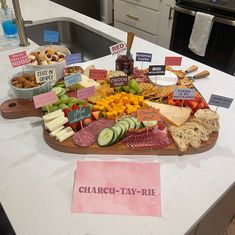 a large platter of cheese and meats on a kitchen counter with signs that say chardis - tay - rie