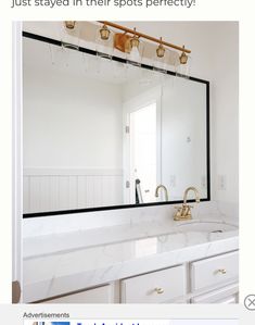 a bathroom with a large mirror above the sink and gold faucets on the wall