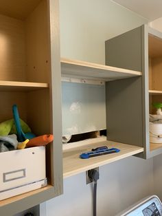 an open cabinet with tools and other items on the shelf in front of it, next to a cell phone