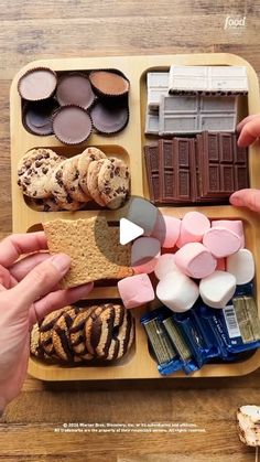 a wooden tray filled with lots of different types of cookies and marshmallows