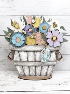 a basket filled with lots of flowers on top of a white wooden floor next to a wall