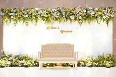 a white couch sitting in front of a wall with flowers and greenery on it