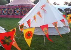 several tents with flags hanging from them in the grass