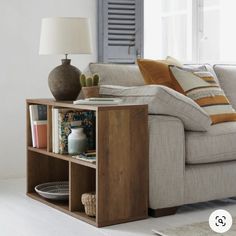 a living room with a couch, coffee table and bookshelf in front of the window