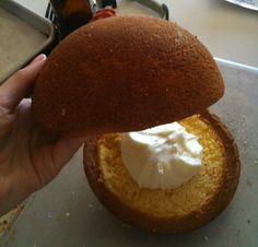 a person is holding up a piece of bread with whipped cream on top