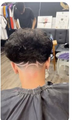 a man getting his hair cut in a barbershop with another person behind him