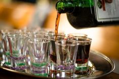 a tray filled with glasses and a bottle of wine being poured into the glass cups