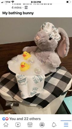 a stuffed rabbit sitting on top of a toilet next to two rubber ducky toys