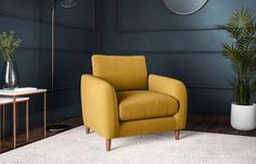 a yellow chair sitting on top of a white rug in a living room next to a plant