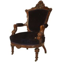 an ornate wooden chair with black velvet upholstered back and arm rests on a white background