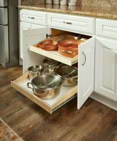 an open cabinet with pots and pans in it